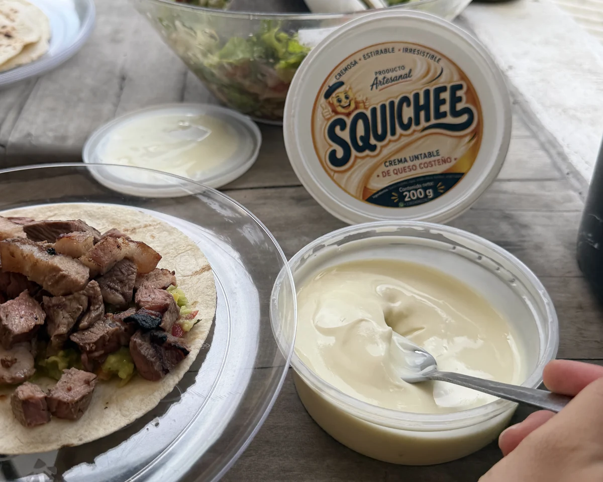 Squichee abierto con su cuchara, junto a un plato sobre la mesa de madera, en una presentación anterior
